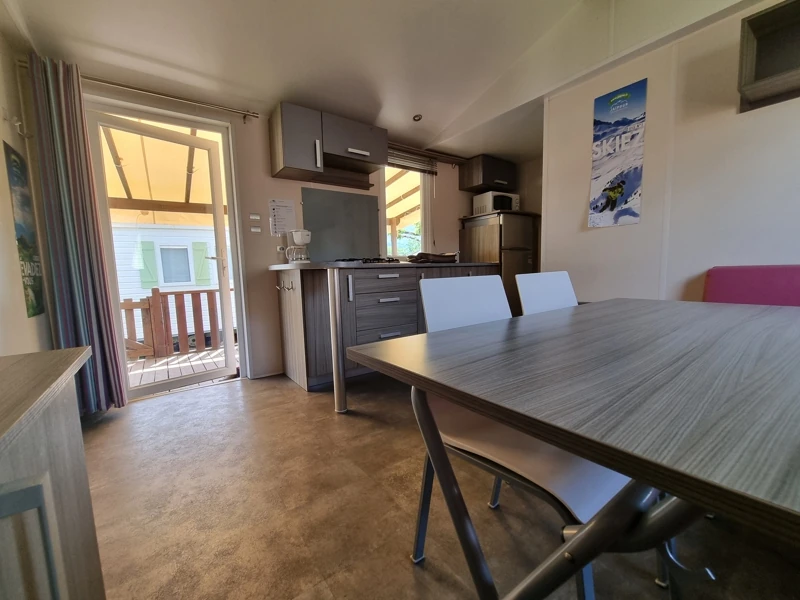 Espace à vivre d'un mobil-home avec coin repas et cuisine équipée