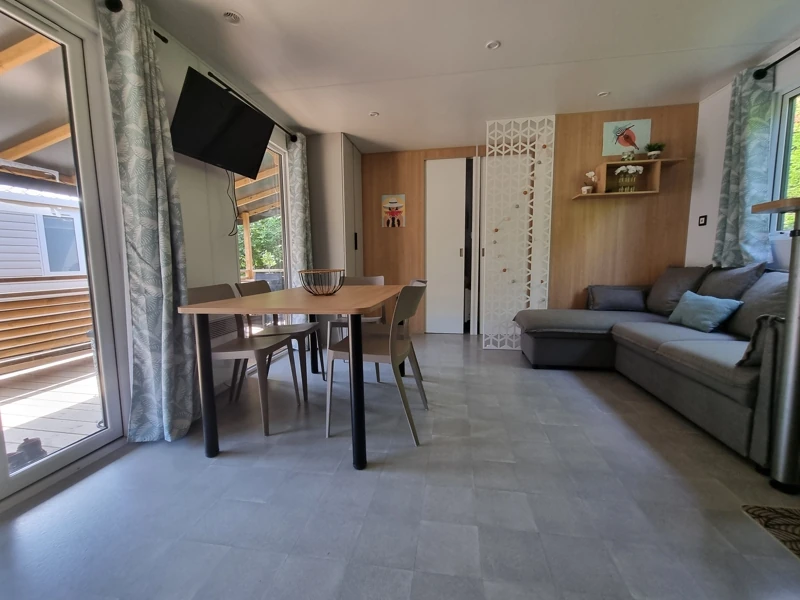 Vue intérieur de l'espace à vivre d'un mobil-home avec table, chaise et canapé