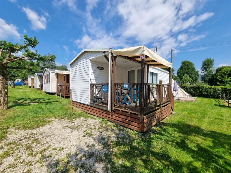 Un mobil-home avec terrasse extérieur sur un emplacement verdoyant au camping