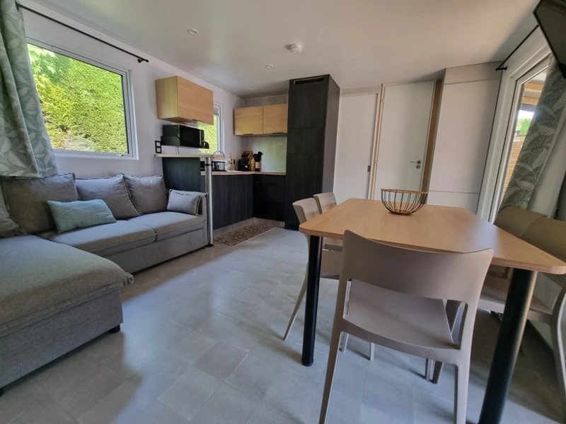 Espace de vie dans un mobil-home avec espace repas, salon et cuisine équipée