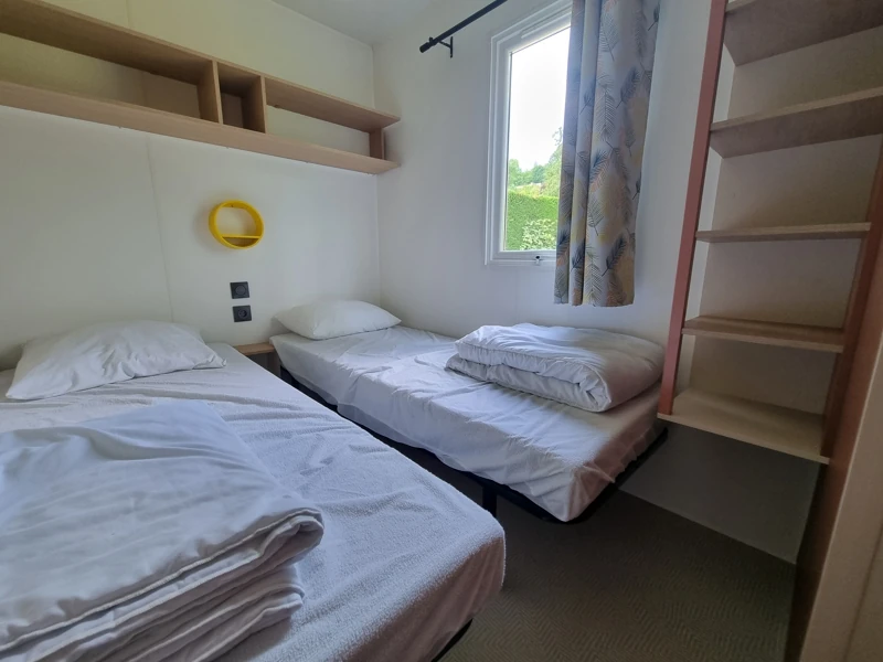 Vue d'une chambre avec 2 lits et rangements en mobil-home