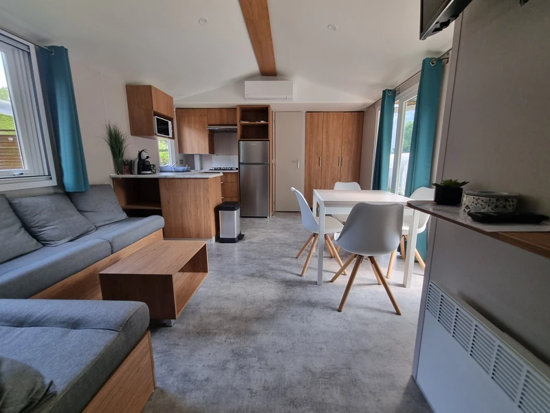 Vue intérieure d'un mobil-home spacieux et lumineux avec cuisine, coin repas et salon