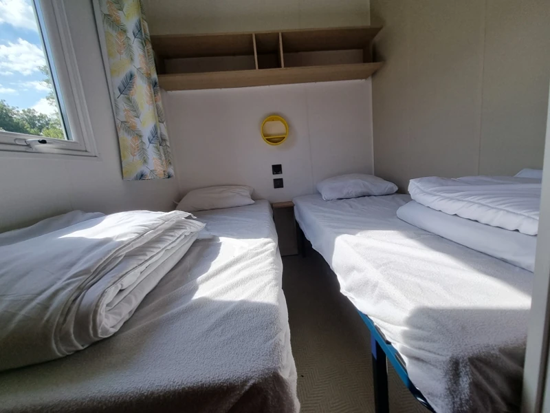 Vue d'une chambre avec deux lits simples en mobil-home