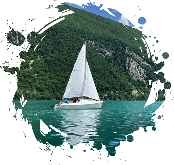 Un petit voilier navigue sur un lac avec 2 personnes à bord