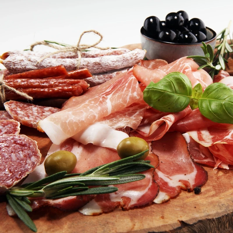 Un planche en bois sur lequel sont disposées différentes sortes de charcuterie.