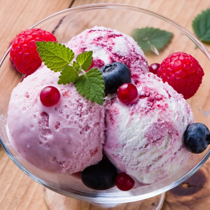 Appétissante coupe de glace composée de 3 boules et de fruits rouges frais : framboises, myrtilles, groseilles et feuilles de menthe