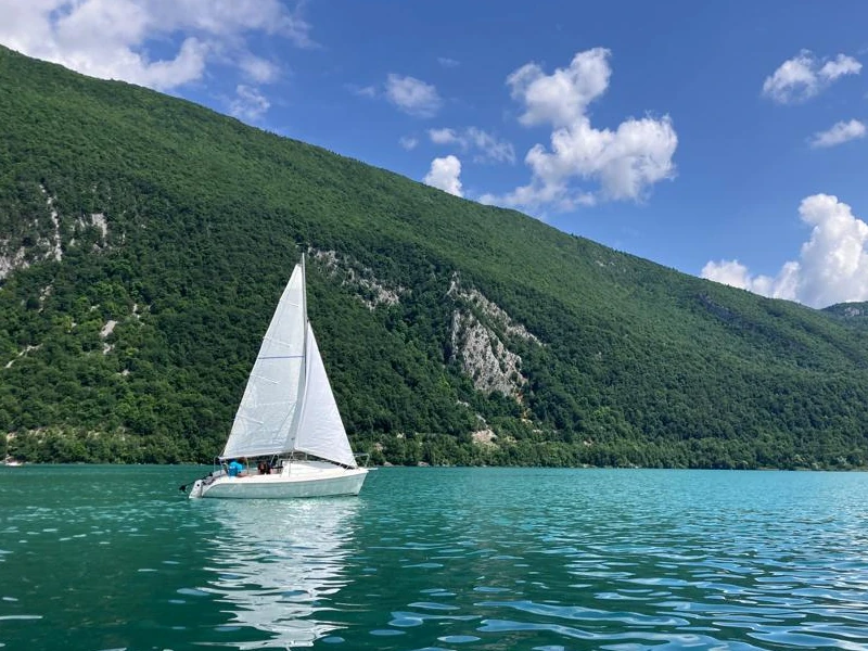 Voilier toutes voiles dehors navigue sur le lac avec la montagne en second plan