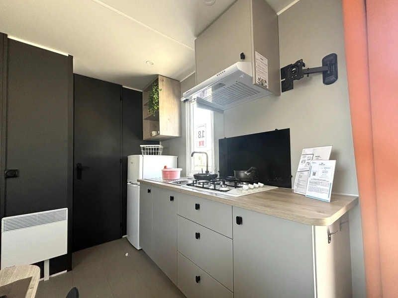 Cuisine équipée avec plaque de cuisson, hotte, réfrigérateur et rangements dans le mobil-home Laguna Colorada